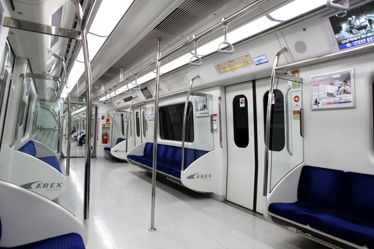 Sièges bleus et allée dégagée dans un train d'aéroport AREX