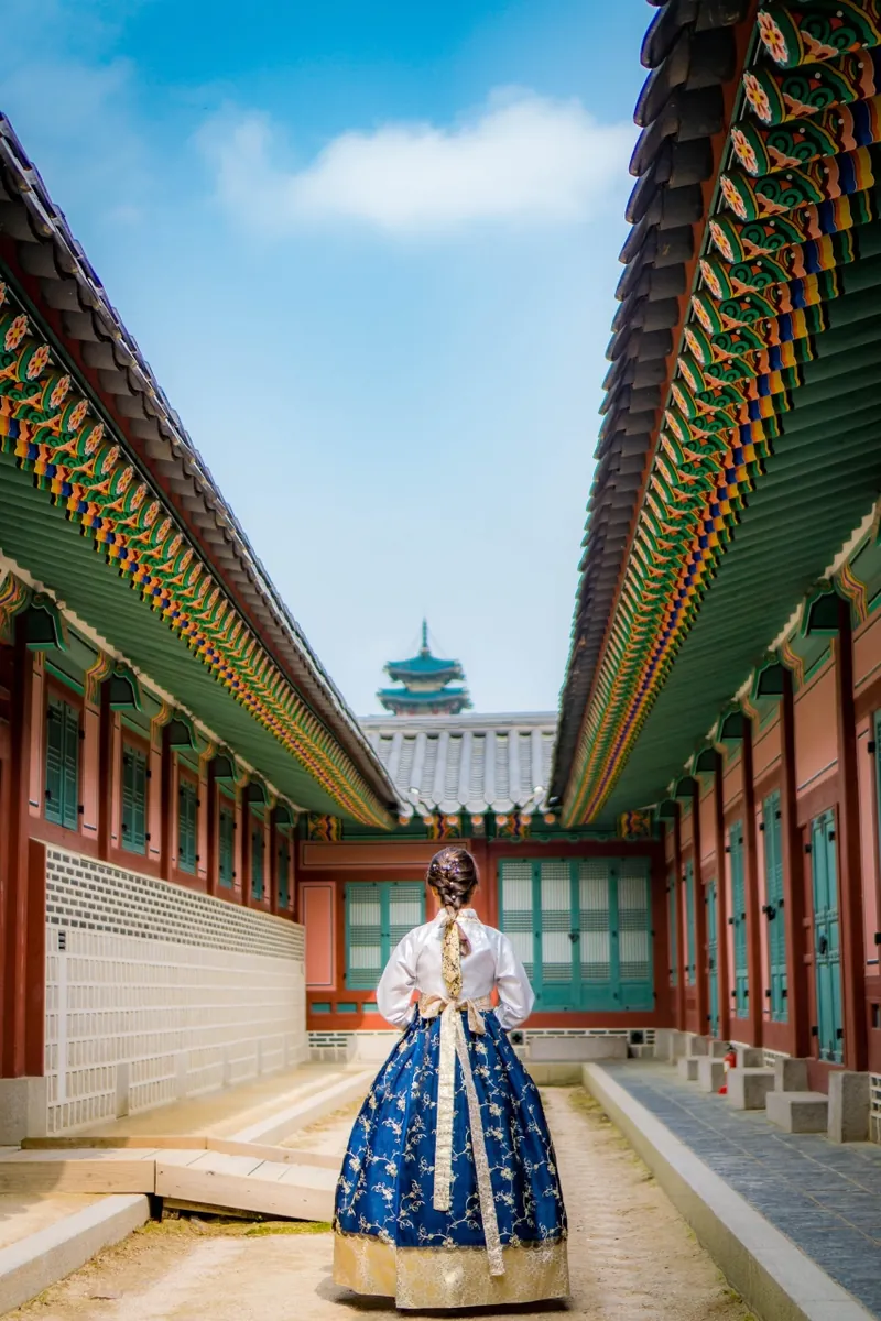Back view of a visitor in hanbok crossing a Gyeongbokgung Palace courtyard