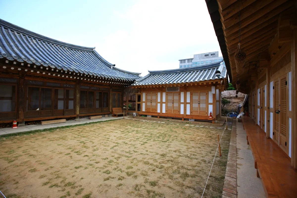 Wooden guest-room doors and tiled hanok roofs face an open courtyard at Pungnamheon in Jeonju