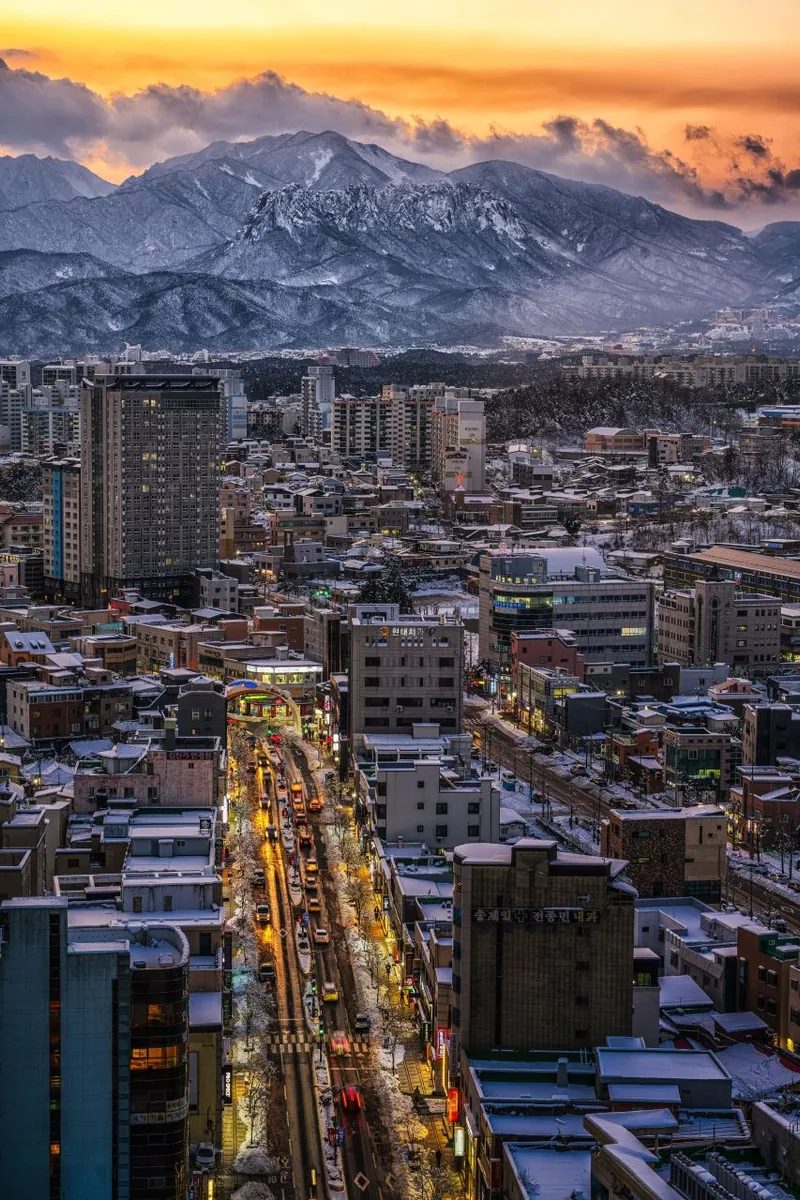 白雪覆盖束草市区，冬日夕阳映照雪岳山山脊