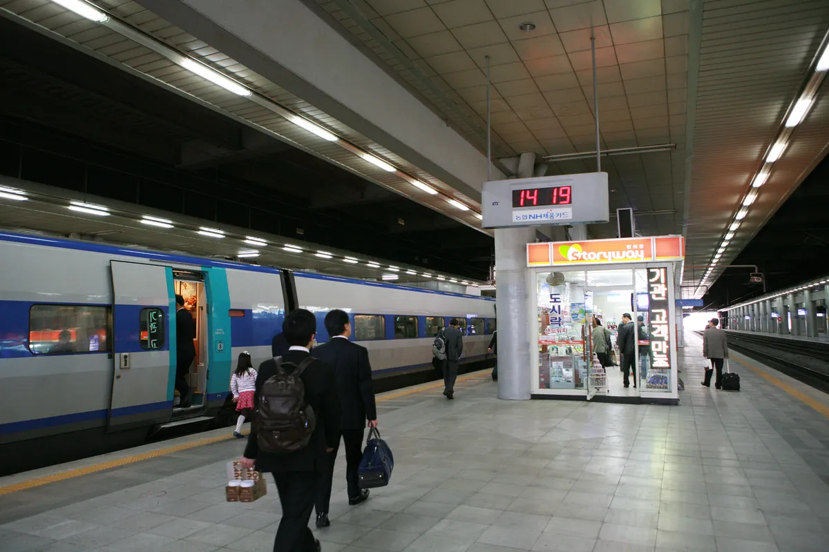 乘客在首尔站站台上，沿蓝银色列车旁步行