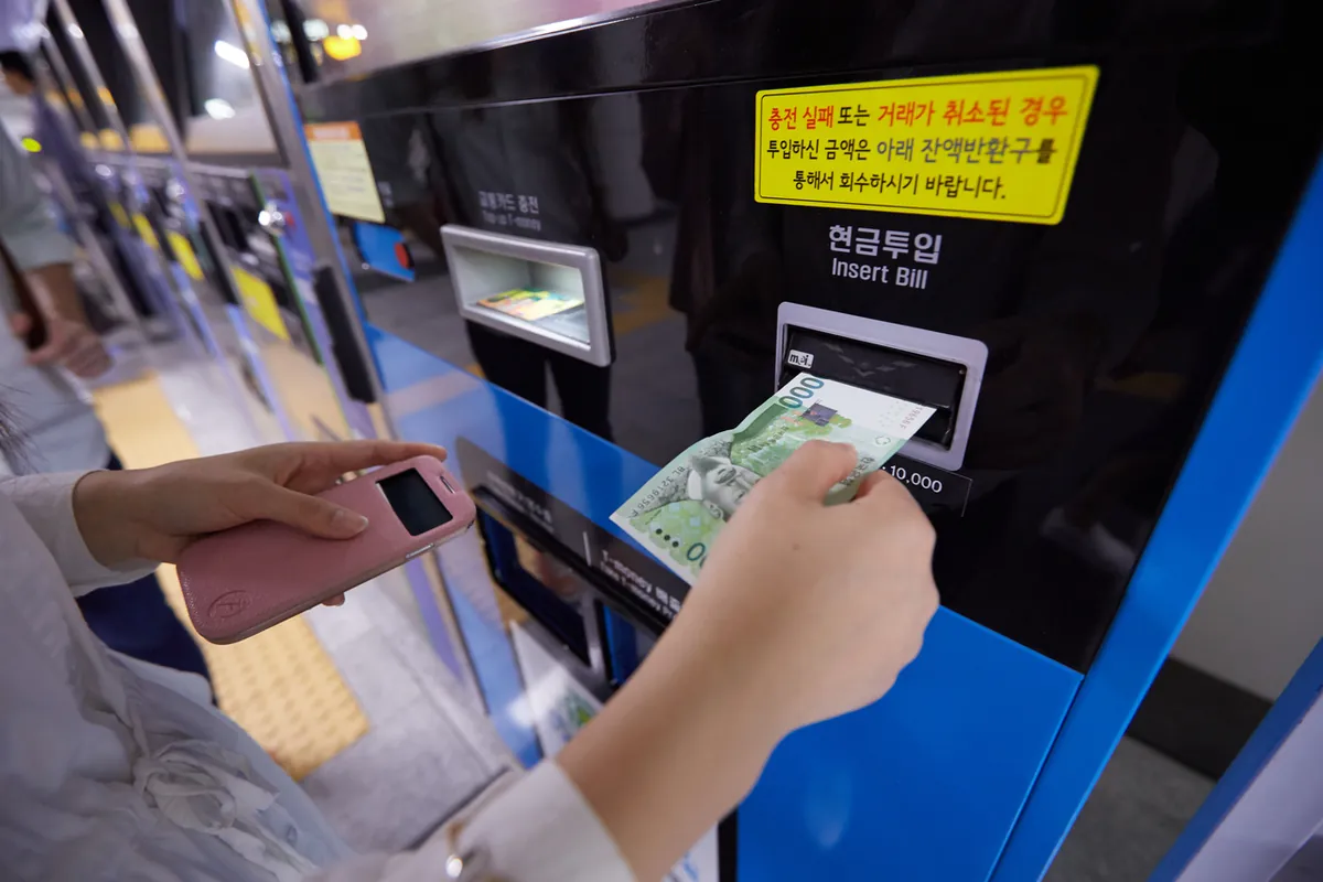 ソウルの地下鉄券売機・チャージ機に現金を入れる乗客