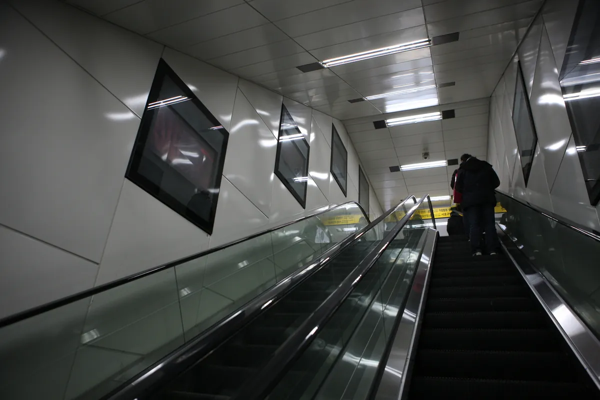 ผู้โดยสารขึ้นบันไดเลื่อนภายในสถานีรถไฟใต้ดินยังแจ