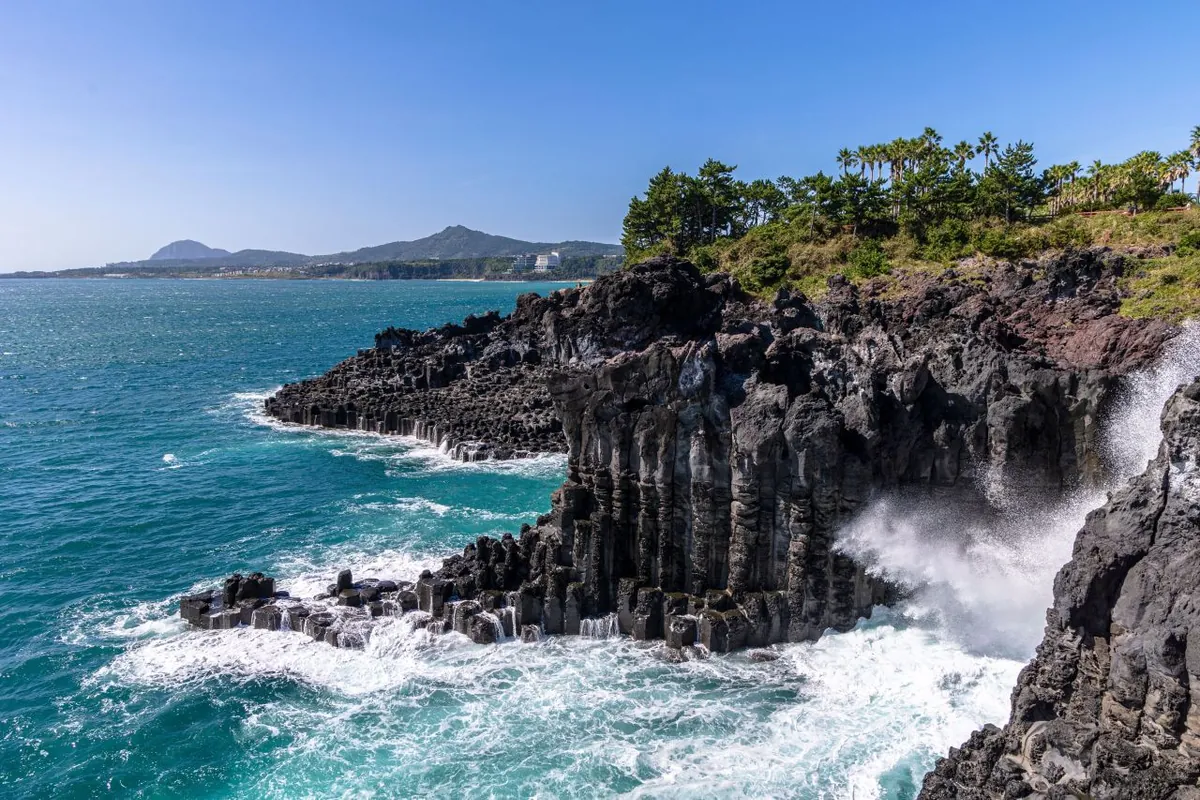 Cột bazan sẫm màu trên nước xanh ngọc ở bờ Daepo Jeju