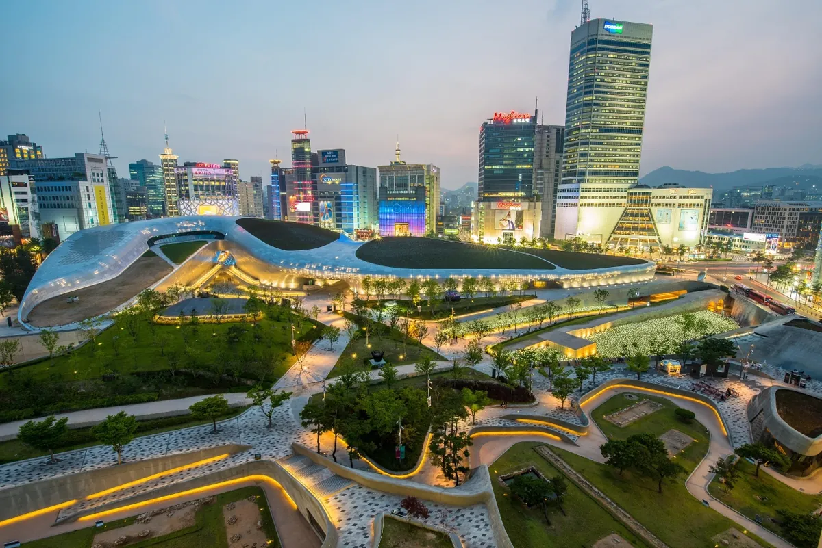 Mái cong có đèn của Dongdaemun Design Plaza giữa tháp đô thị lúc chạng vạng