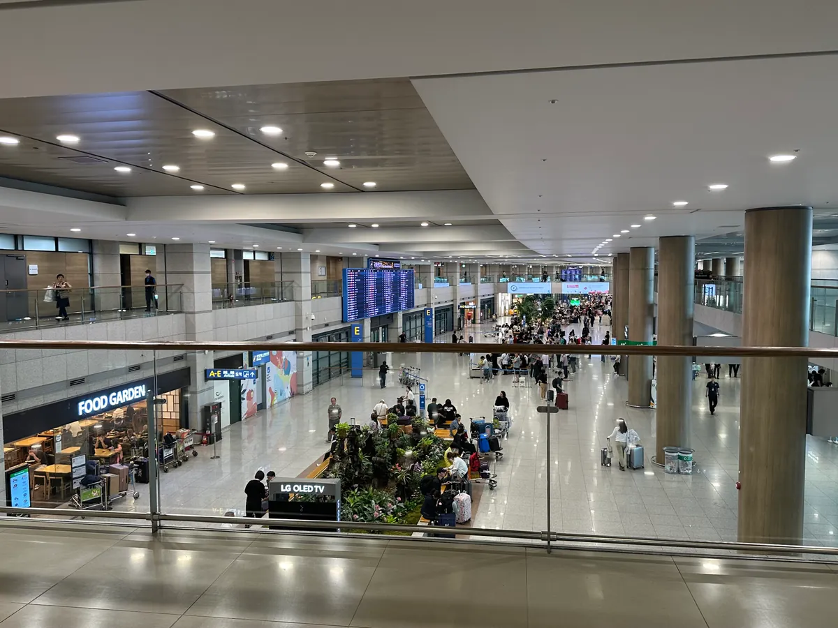 Sảnh đến công cộng với cửa hàng và hành khách chờ tại Nhà ga 1 sân bay Incheon