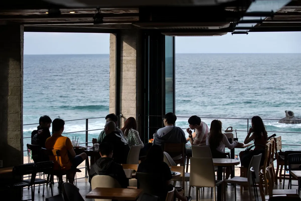 Bàn cà phê cạnh cửa sổ lớn nhìn ra biển ở Anmok