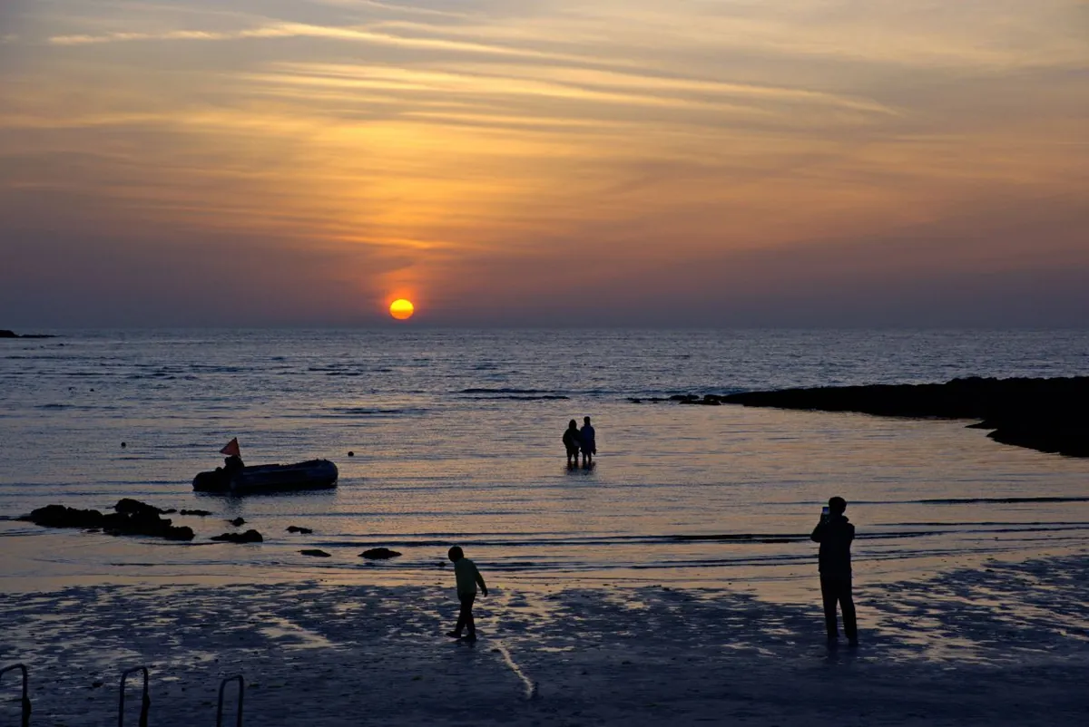 Sun setting across calm water at Hyeopjae Beach on western Jeju