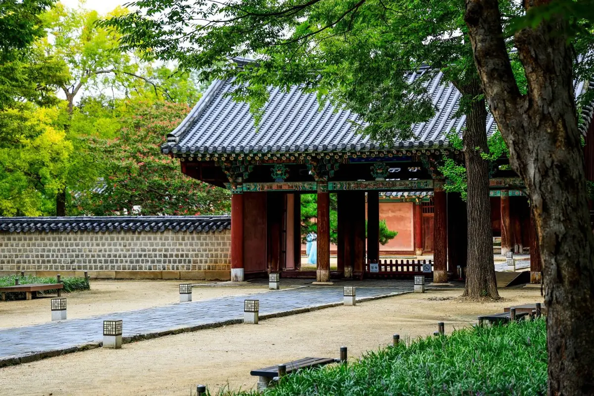 Traditional gate and green courtyard trees inside Gyeonggijeon in Jeonju