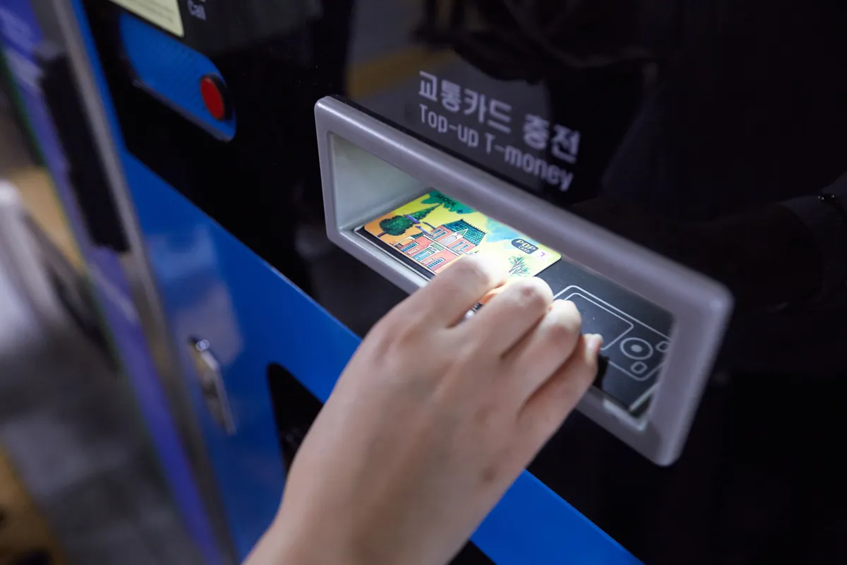Main posant une carte de transport sur un lecteur de recharge de métro