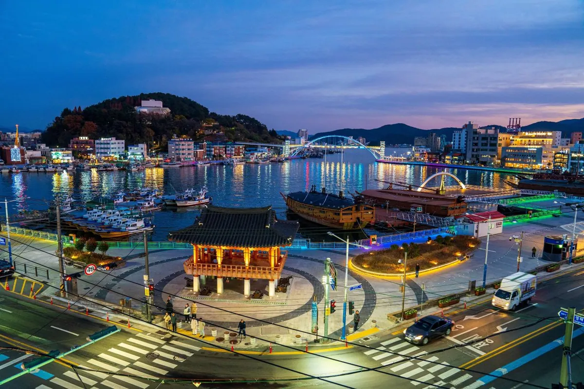 Gangguan harbor, illuminated pedestrian bridge and waterfront streets at dusk