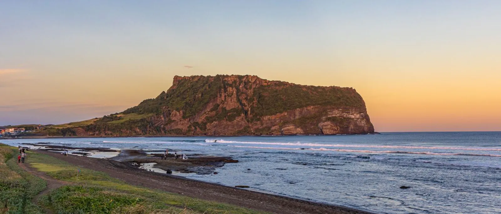 Seongsan Ilchulbong rising above Jeju's eastern coast at sunset