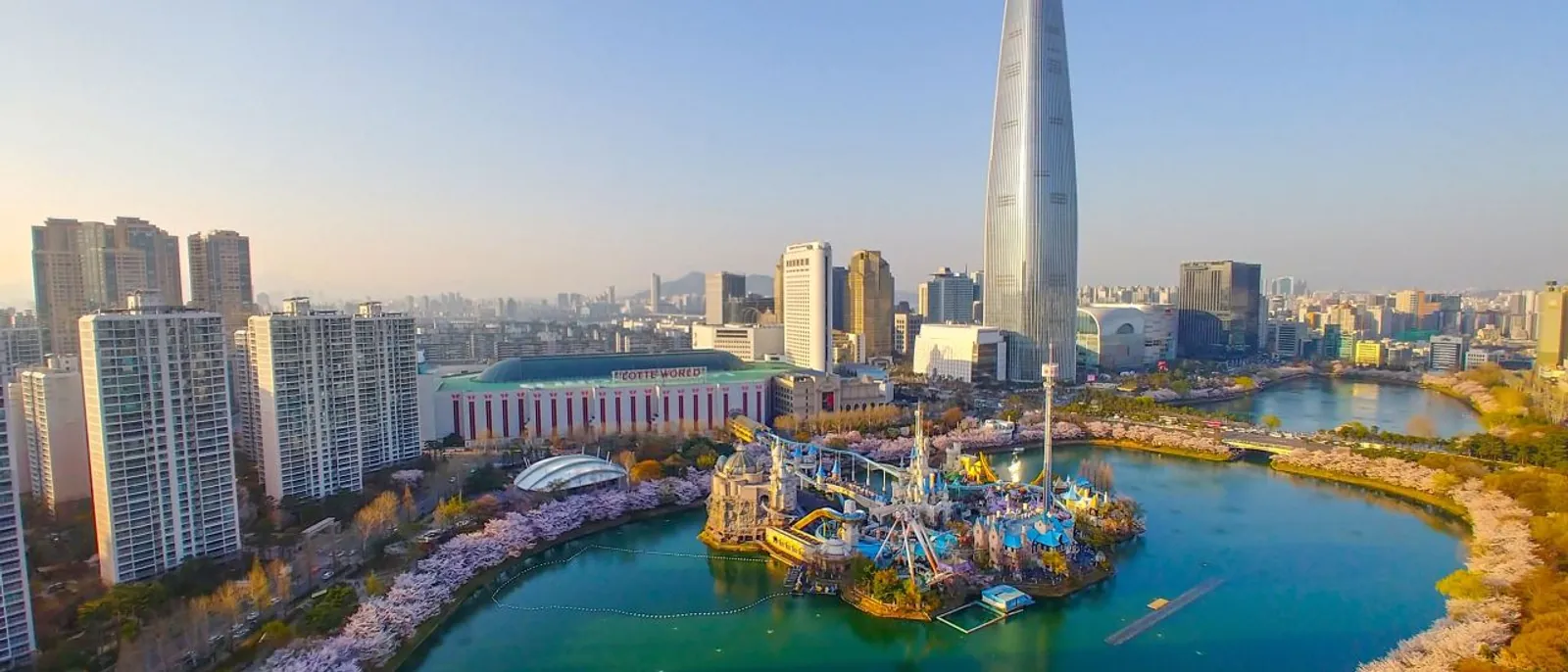 Lotte World Magic Island beside Seokchon Lake with Lotte World Tower rising behind it